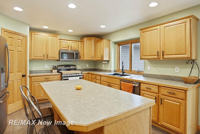 kitchen with a center island, sink, appliances with stainless steel finishes, wood-type flooring, and a breakfast bar area