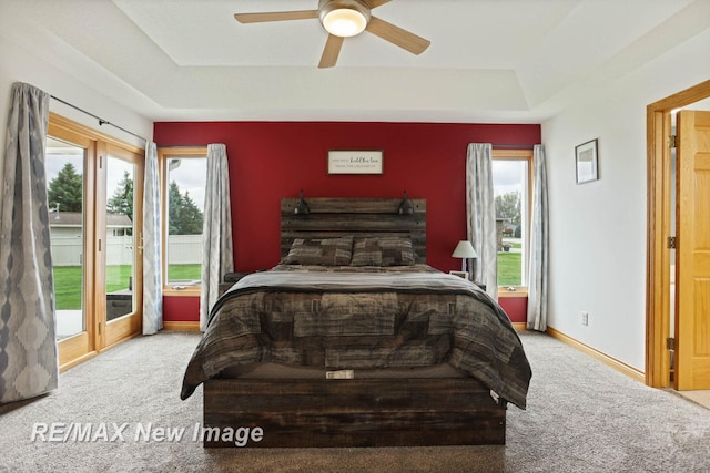 carpeted bedroom with access to outside, ceiling fan, and a tray ceiling