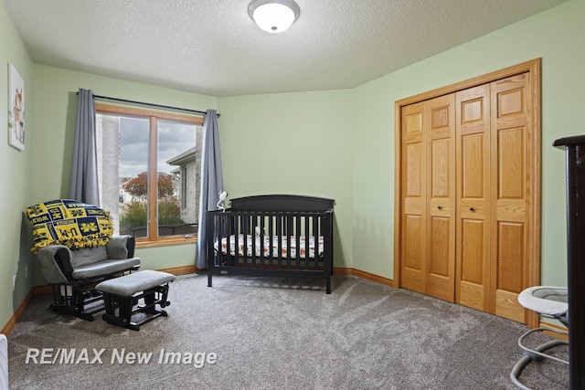 carpeted bedroom with a closet, a nursery area, and a textured ceiling