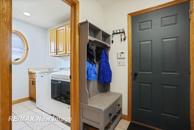 clothes washing area featuring cabinets, light tile patterned floors, and washing machine and dryer