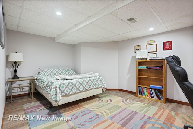 bedroom with a paneled ceiling and hardwood / wood-style flooring