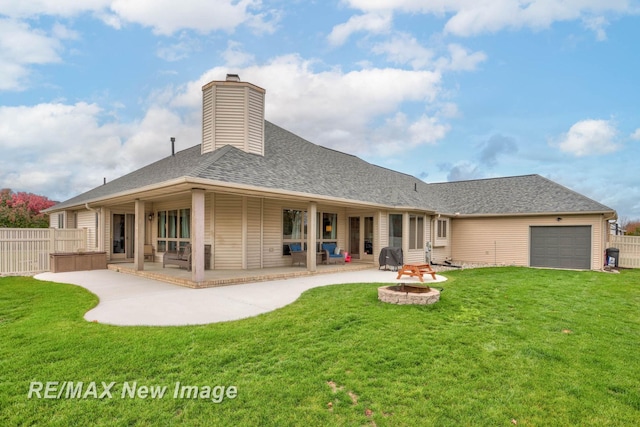 back of house featuring a lawn, a patio area, and an outdoor fire pit