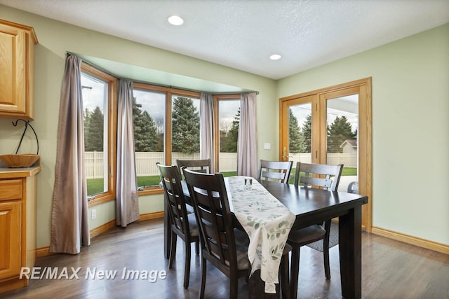 dining area featuring a textured ceiling, dark hardwood / wood-style flooring, and a wealth of natural light