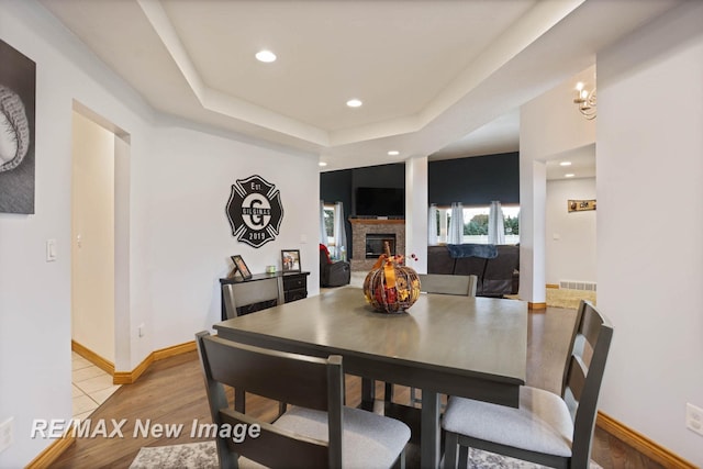 dining area featuring a raised ceiling, light wood-type flooring, and a chandelier