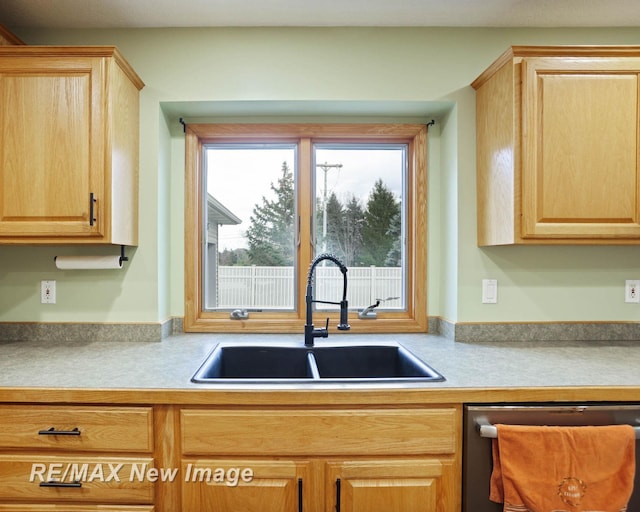 kitchen with light brown cabinetry, stainless steel dishwasher, and sink