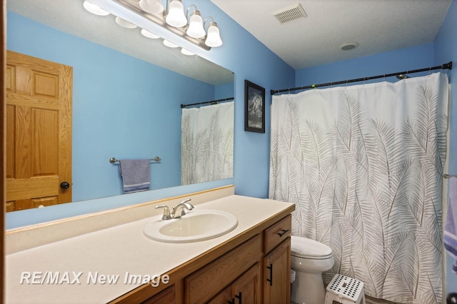 bathroom with vanity, toilet, and a textured ceiling