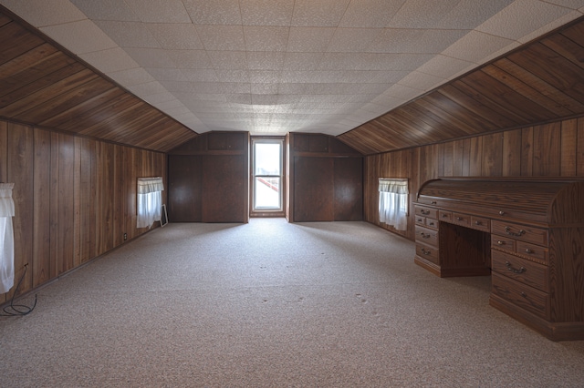 additional living space with light colored carpet, vaulted ceiling, and wood walls