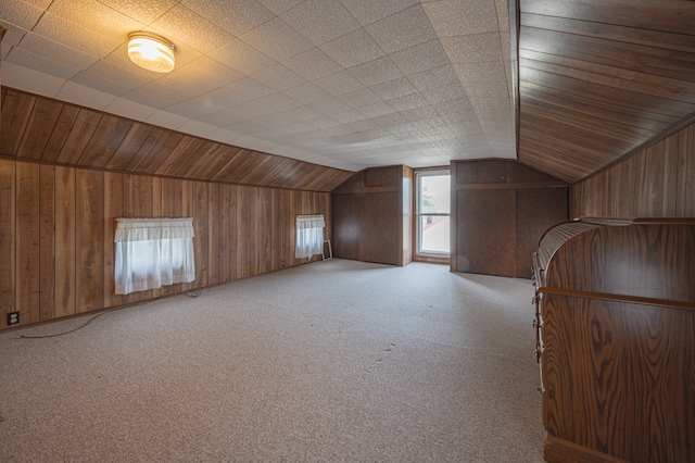 bonus room featuring light colored carpet, vaulted ceiling, and wooden walls