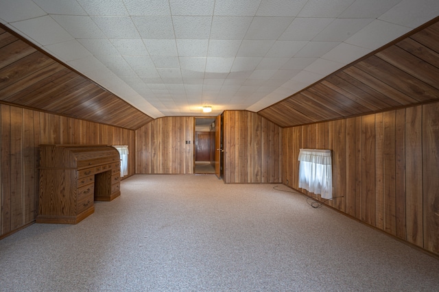 bonus room featuring carpet flooring, wood walls, and vaulted ceiling