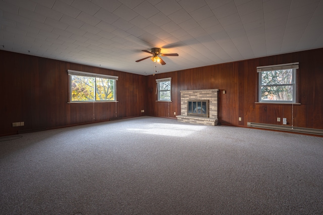 unfurnished living room featuring a brick fireplace, ceiling fan, carpet floors, and a baseboard heating unit