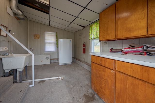 kitchen with white fridge, plenty of natural light, wood walls, and lofted ceiling