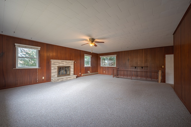 unfurnished living room featuring carpet flooring, a healthy amount of sunlight, and wood walls