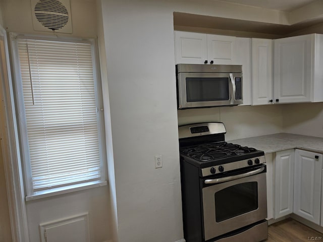 kitchen featuring white cabinets, appliances with stainless steel finishes, and light wood-type flooring