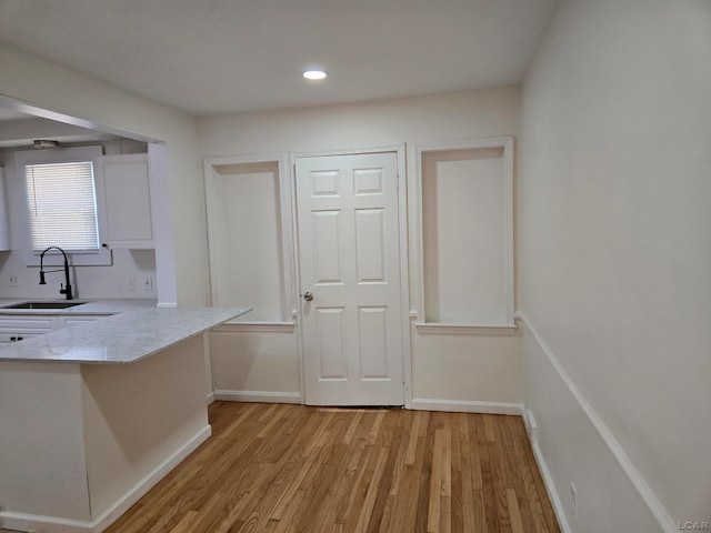 kitchen featuring kitchen peninsula, sink, white cabinets, and light hardwood / wood-style floors