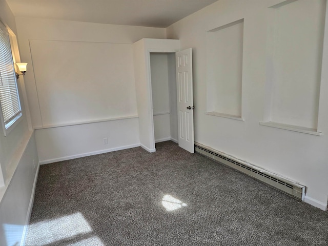 empty room with dark carpet and a baseboard radiator