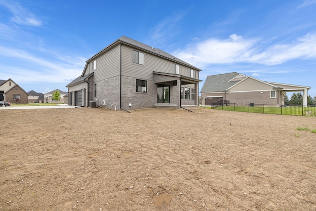 rear view of property featuring central AC and a garage