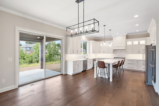 kitchen with a wealth of natural light, white cabinets, dark hardwood / wood-style floors, and a kitchen island