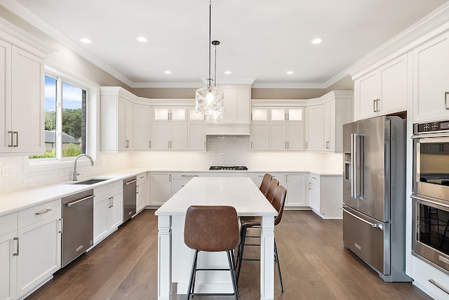 kitchen with sink, a kitchen island, dark wood-type flooring, and appliances with stainless steel finishes