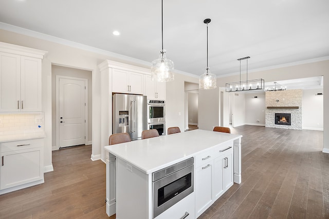 kitchen with pendant lighting, dark hardwood / wood-style floors, a fireplace, white cabinetry, and stainless steel appliances