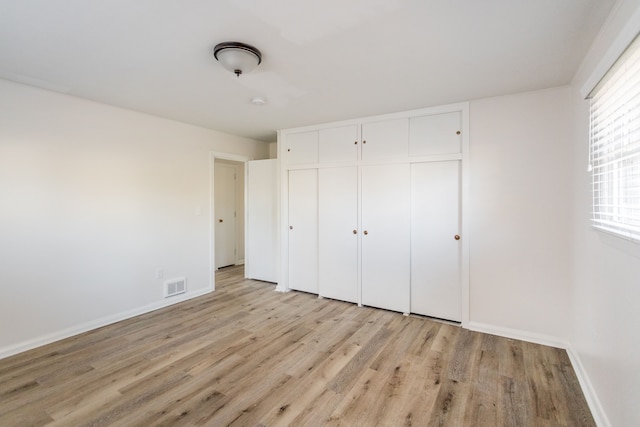 unfurnished bedroom with a closet and light wood-type flooring