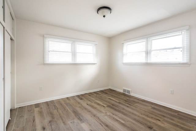 unfurnished bedroom featuring a closet, wood-type flooring, and multiple windows