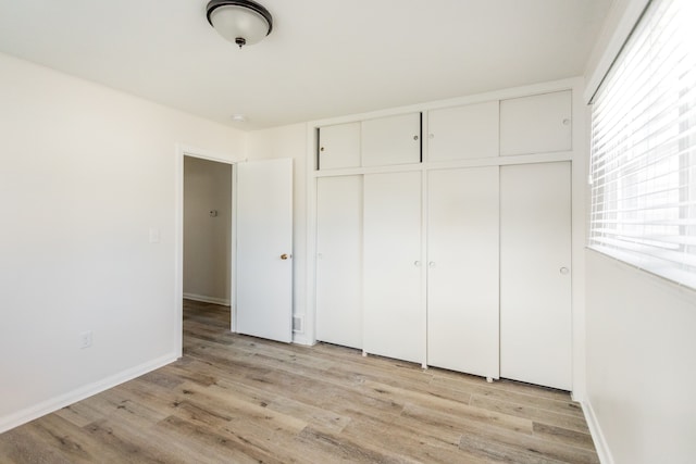 unfurnished bedroom with light wood-type flooring and a closet