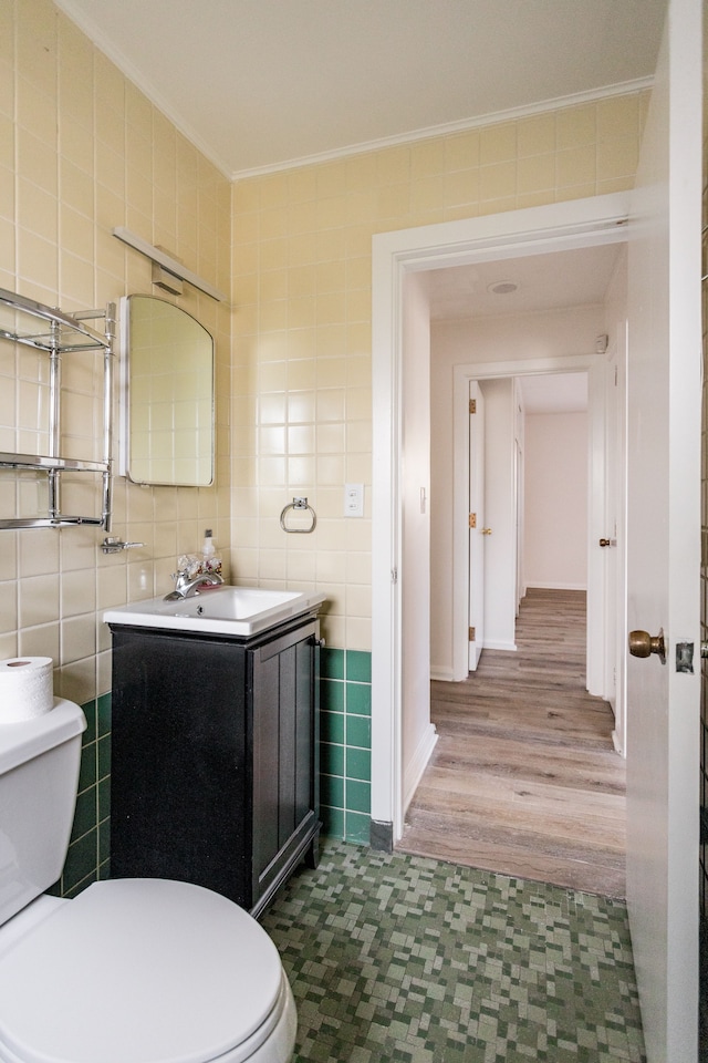 bathroom featuring wood-type flooring, vanity, tile walls, and ornamental molding