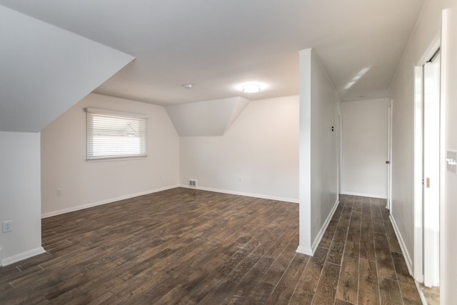 additional living space featuring dark wood-type flooring and vaulted ceiling