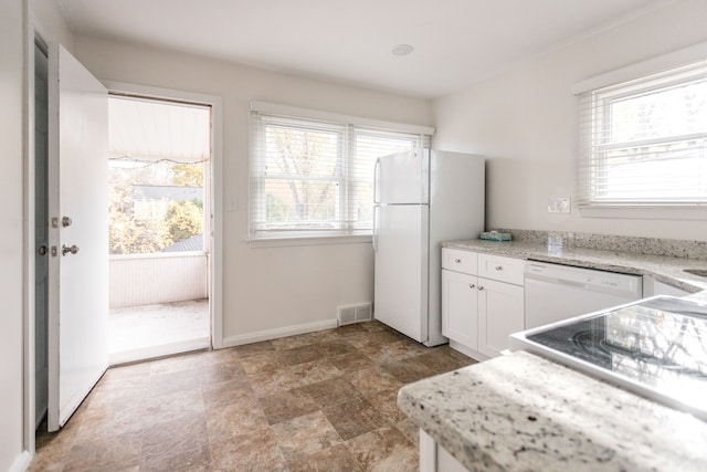 kitchen with light stone countertops, white appliances, white cabinetry, and a healthy amount of sunlight