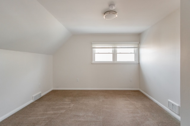 additional living space with light colored carpet and vaulted ceiling