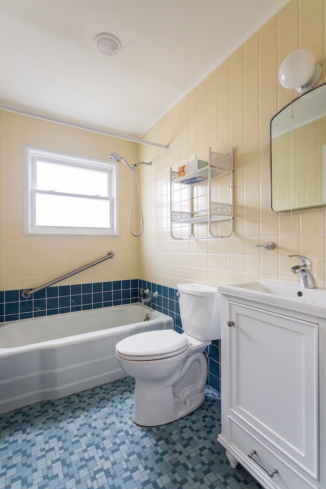 full bathroom featuring vanity, tiled shower / bath combo, toilet, and tile walls