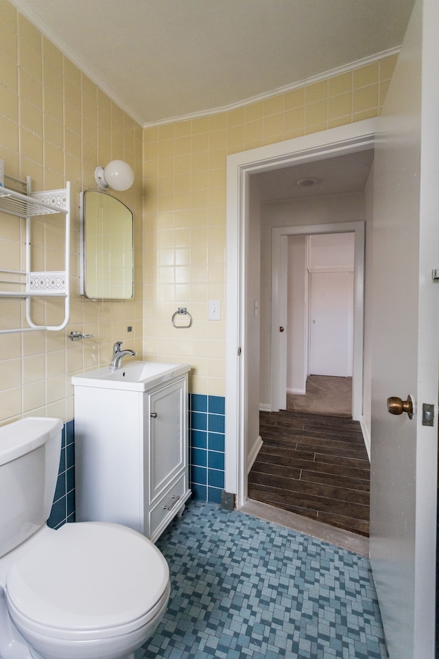 bathroom with hardwood / wood-style floors, vanity, toilet, ornamental molding, and tile walls