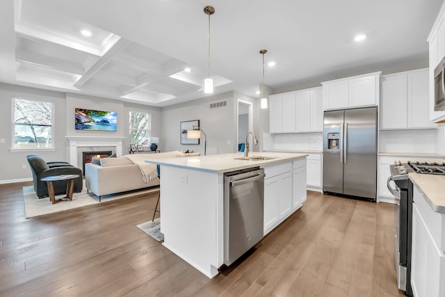 kitchen with white cabinets, stainless steel appliances, a kitchen island with sink, and sink