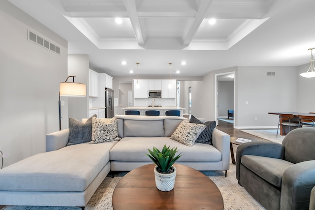 living room featuring coffered ceiling, beamed ceiling, light hardwood / wood-style floors, and crown molding