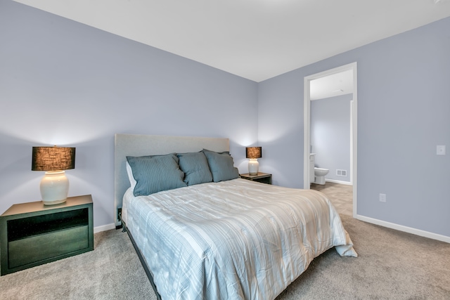 bedroom featuring ensuite bath and carpet flooring