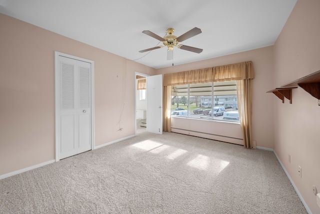 unfurnished bedroom with ensuite bath, light colored carpet, ceiling fan, a baseboard heating unit, and a closet