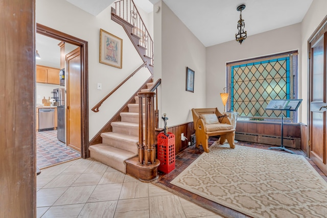 foyer entrance with baseboard heating and wooden walls