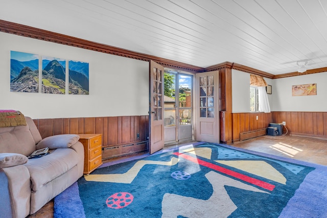 carpeted living room featuring wood walls, wood ceiling, crown molding, and a baseboard radiator