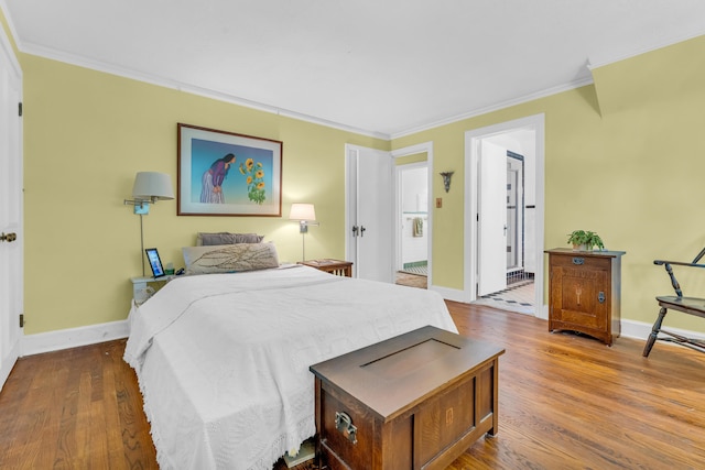 bedroom with connected bathroom, wood-type flooring, and ornamental molding