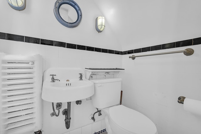 bathroom with radiator, tile walls, lofted ceiling, and toilet