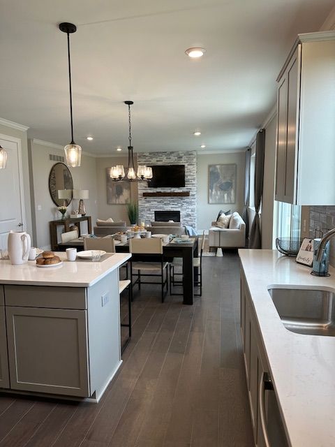 kitchen with sink, dark hardwood / wood-style flooring, pendant lighting, gray cabinets, and a fireplace