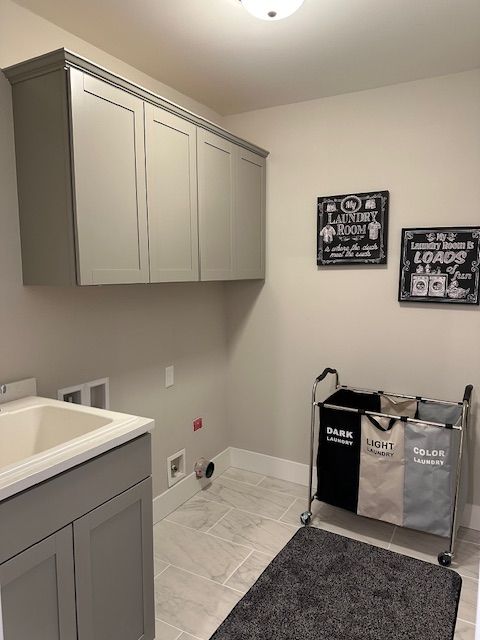 washroom with cabinets, hookup for a washing machine, and sink