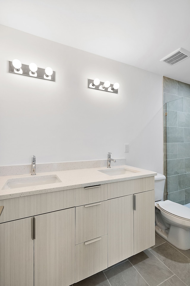 bathroom featuring tile patterned floors, vanity, toilet, and a tile shower