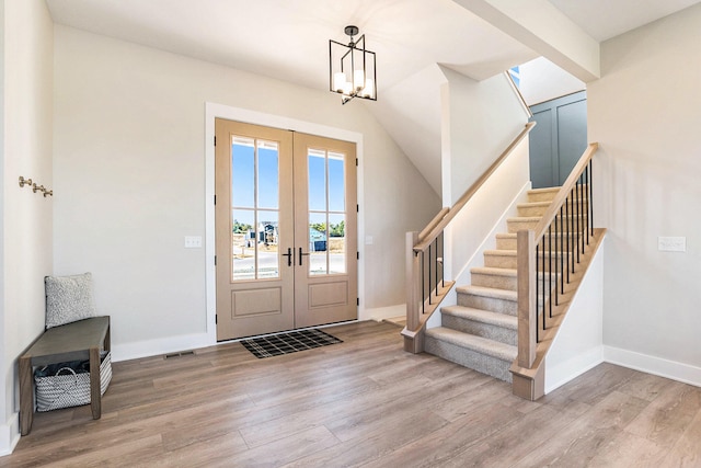 entrance foyer with wood-type flooring, french doors, and a notable chandelier