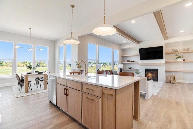 kitchen with a center island with sink, sink, light hardwood / wood-style flooring, light brown cabinetry, and decorative light fixtures