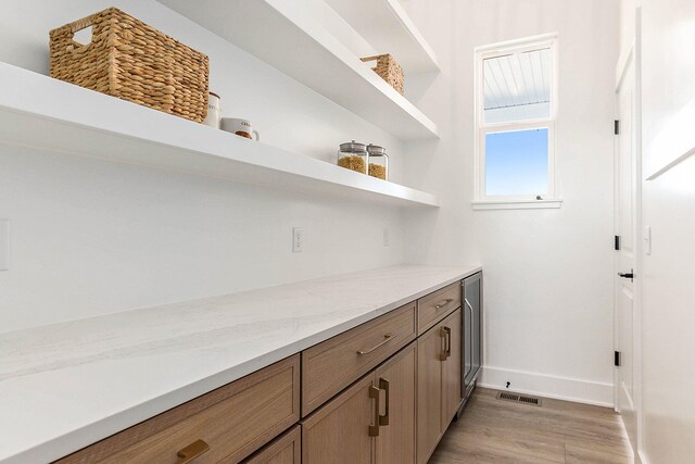 bar with light stone counters and light hardwood / wood-style flooring