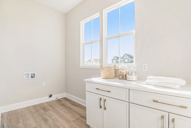 clothes washing area featuring hookup for a washing machine, light hardwood / wood-style flooring, and cabinets