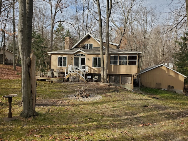 exterior space featuring a sunroom, a deck, and a lawn