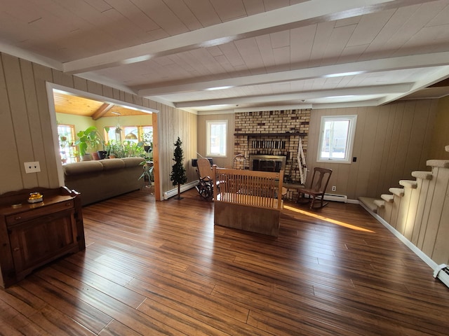 living room featuring a baseboard heating unit, wooden walls, dark hardwood / wood-style floors, a brick fireplace, and beamed ceiling