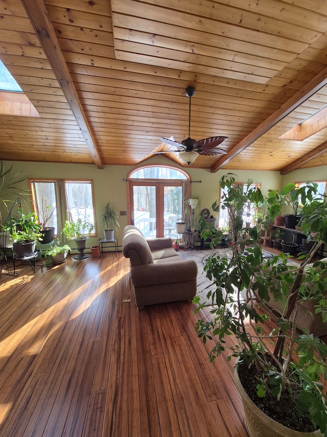 living room featuring wood-type flooring, vaulted ceiling with skylight, ceiling fan, and wood ceiling